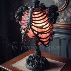 a lamp that is sitting on top of a table with roses in the shape of a skeleton