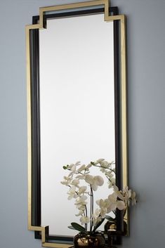 a vase with flowers sitting on top of a table in front of a large mirror