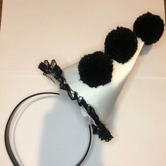 a white hat with black pom - poms on it sitting on top of a table