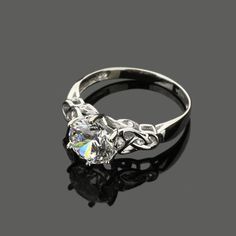 a white gold ring with an oval cut diamond in the center and leaves on each side