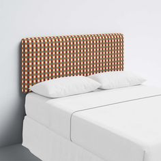 an upholstered headboard on a bed with white sheets