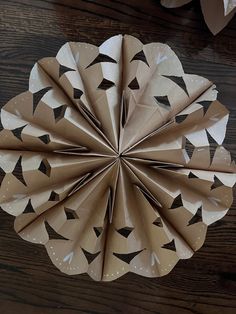 an origami flower made out of brown paper on a wooden table with other items