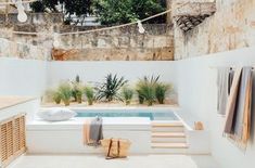 an outdoor jacuzzi with towels hanging from the ceiling and potted plants on the wall