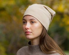 a young woman wearing a beige hat and brown turtle neck sweater looking at the camera