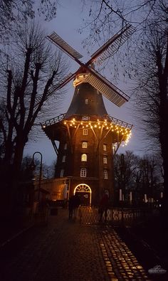 the windmill is lit up with christmas lights