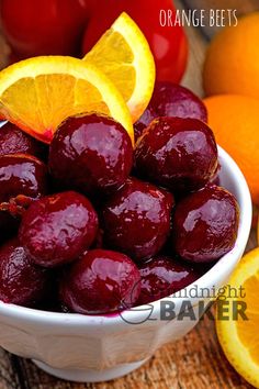 a bowl filled with oranges and cherries on top of a wooden table next to other fruit