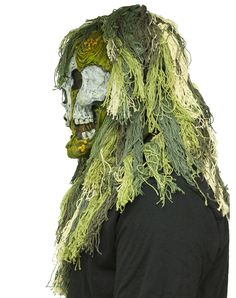 a man with long hair wearing a green and white zombie mask on his head, covered in moss