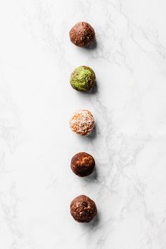 four different types of doughnuts lined up on a white counter top with sprinkles