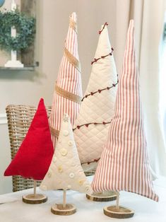 three decorative christmas trees are sitting on a table with red and white striped pillowes