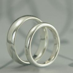 two wedding rings sitting side by side on a white surface with circles in the background