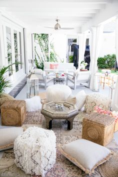 a living room filled with white furniture and lots of pillows on top of it's floor