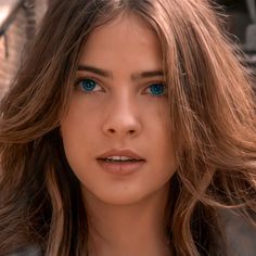 a close up of a person with long hair and blue eyes looking at the camera