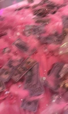 a bunch of money sitting on top of a pile of pink confetti cones