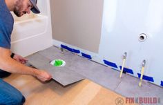 a man sitting on the floor in front of a wall with blue and green tape