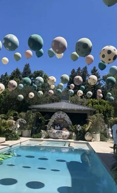 an outdoor swimming pool with balloons floating in the air