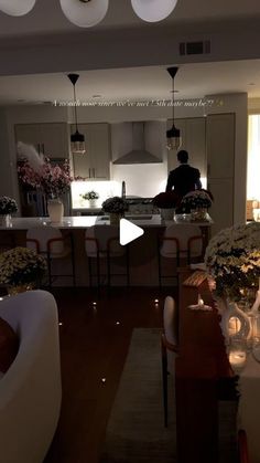 a man is standing in the middle of a living room with flowers on the table