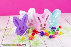 three bunny shaped candy boxes sitting on top of a wooden table next to jelly beans