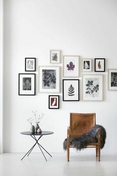 a white room with pictures on the wall and a chair in front of a table