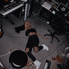 a woman laying on the floor in front of an assortment of musical instruments and keyboards