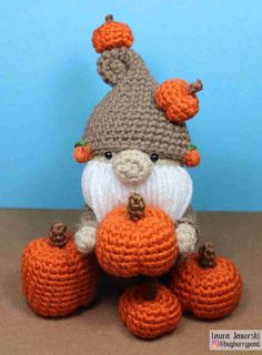 a knitted gnome sitting on top of pumpkins