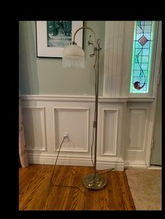 the floor lamp is in front of a wall with stained glass windows and wood floors