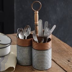 there are many silverware in the tins on the table with forks and spoons