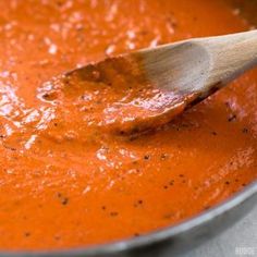 a wooden spoon in a pot of tomato sauce