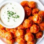 a white plate topped with tater tots and a small bowl of ranch dressing