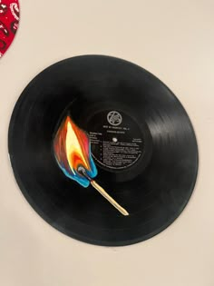 a black record with a colorful flame on it next to a red and white heart