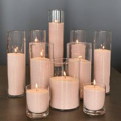 a group of lit candles sitting on top of a wooden table next to each other