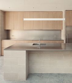 a modern kitchen with stainless steel counter tops and wooden cabinetry, along with an island in the middle