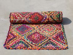 a multicolored rug on the ground next to a potted plant and vase