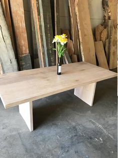 a vase with yellow flowers sitting on top of a table next to stacks of wood