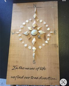 a wooden sign with shells on it that says in the news of life, we find out true direction