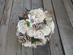 a bridal bouquet with white flowers on a wooden floor in front of wood planks