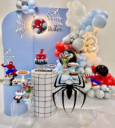 a spiderman themed birthday party with balloons, cake and desserts on the table