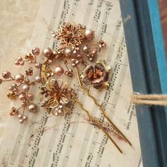 This stunning rustic rose gold-plated hairpin showcases an exquisite blend of vintage rose gold and gold-plated flower filigrees, adorned with shimmering Austrian crystals, pearls and lava stones.  The pearls and crystals, in rich shades of brown, powder almond, and rose gold, add a touch of elegance and warmth. Perfect for making a bold statement, this large hairpin beautifully combines vintage charm with timeless sophistication. Style P062 - Vivid Verve Pin This item is meticulously handcrafted in our studio located in the USA. Materials: - vintage rose gold, shiny rose gold and gold-plated layered flower filigrees - rose gold-plated lava stones - Austrian crystals and pearls - rose gold-plated artistic wire - 24-karat gold-plated pin To preserve the lasting beauty of your pin, it is rec Vintage Adjustable Gold Headpiece, Rose Gold Leaf Hair Piece, Vintage Gold Flower Brooch, Victorian Gold Flower Brooch, Vintage Gold Flower Shaped Brooch, Fairy Hair, Pearl Rose, Artistic Wire, Vintage Rose Gold