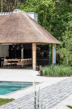 a house with a thatched roof next to a pool