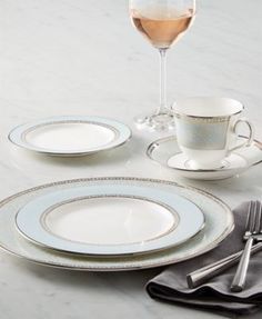 the table is set with silver and white plates, cups, and utensils