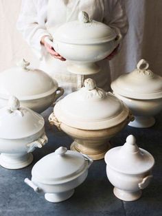 a woman is standing in front of many white dishes