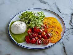 a plate with tomatoes, lettuce and mozzarella on it next to some other vegetables