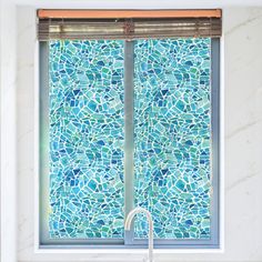 a bathroom window with blue and green tiles on the outside, along with a sink