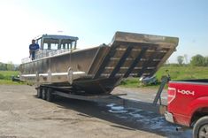 a man standing on the back of a truck with a boat in it's bed