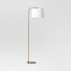 a floor lamp with a white shade on the top, and a gold metal base