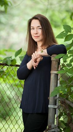 a woman leaning against a fence with her arms crossed