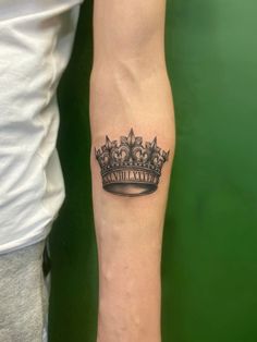 a woman's arm with a crown tattoo on it