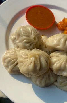 some dumplings are on a white plate with sauce