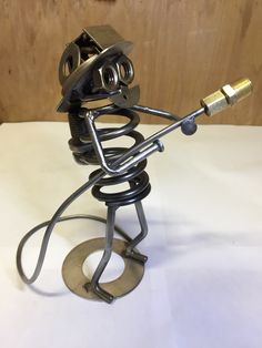 a metal sculpture with a microphone attached to it's head and arms, sitting on a white surface