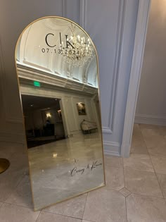 a large mirror sitting on top of a tiled floor next to a wall with a chandelier hanging from it