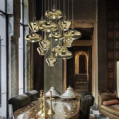 a dining room table with many lights hanging from it's ceiling and chairs around it